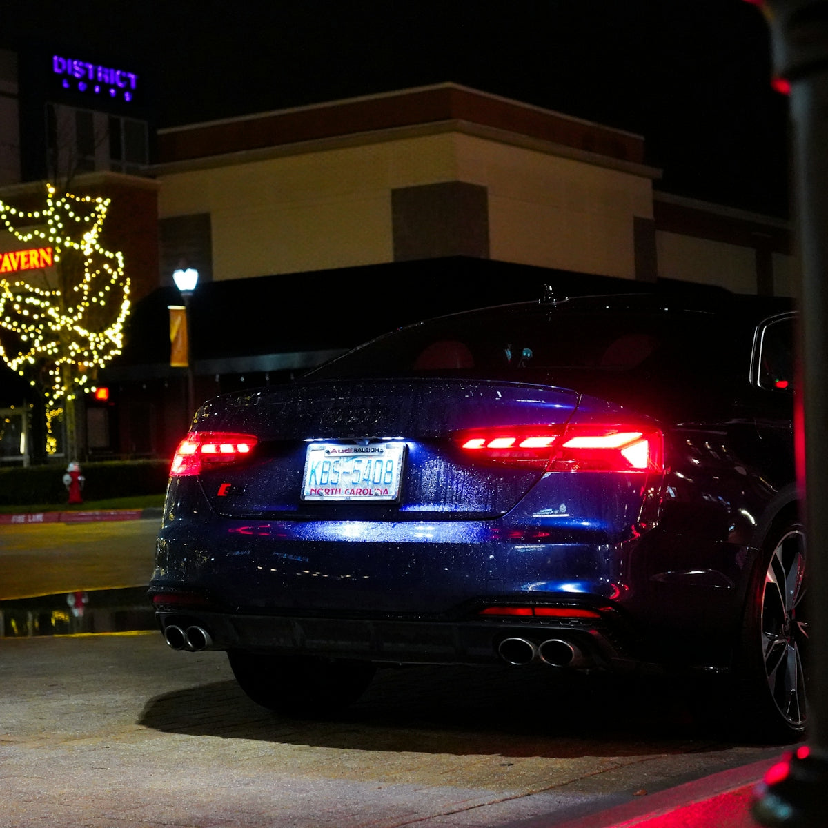 a black car parked in front of a building at night
