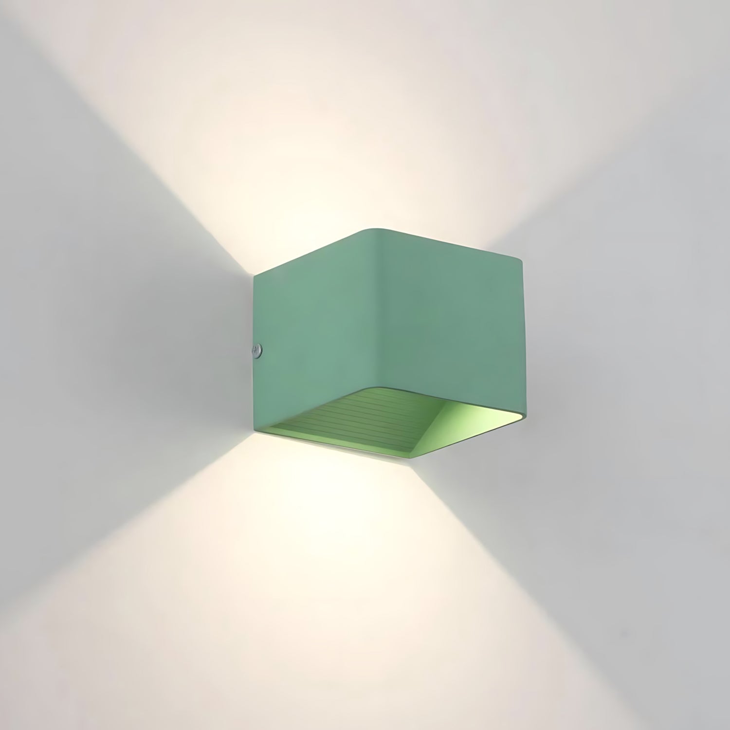 A modern square wall lamp with a sleek design, casting a soft glow on the wall in black, white, and green colors.