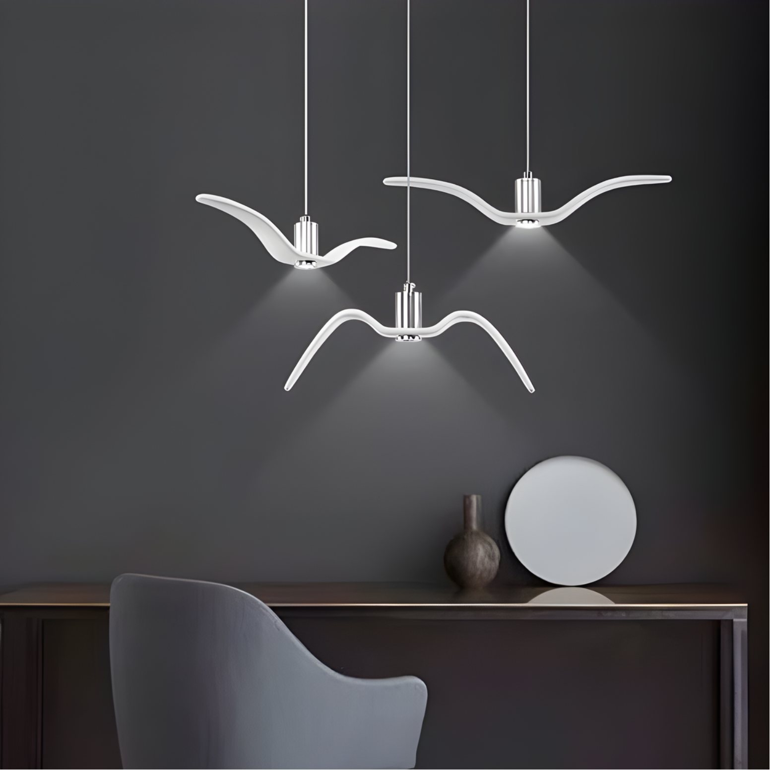 Modern pendant lights hanging above a table with decorative items against a dark wall.