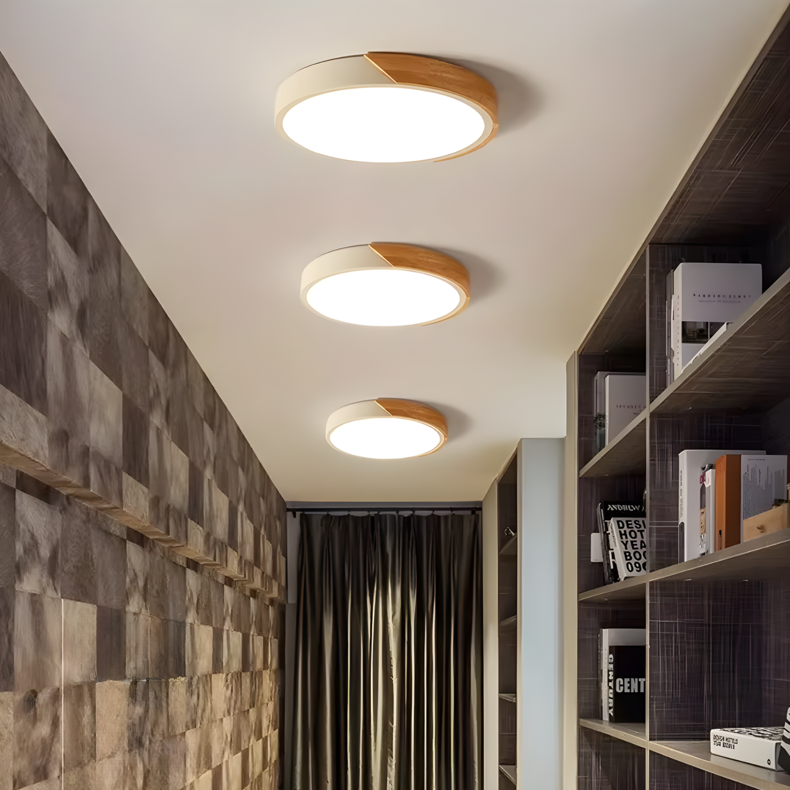 Three ceiling lights in a room with a textured wall and bookshelf.