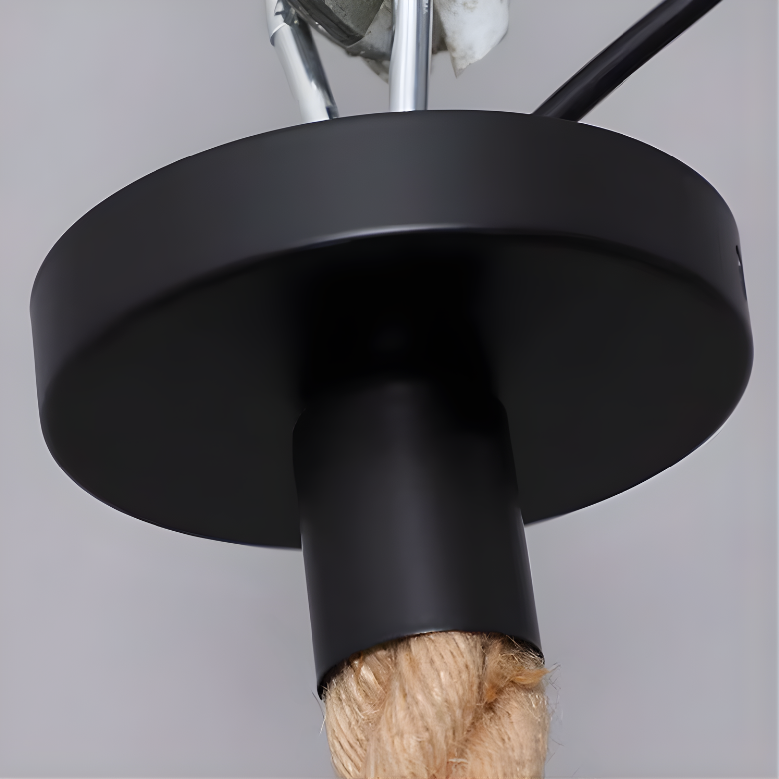 Close-up of a black metal fitting with a rope on a gray background
