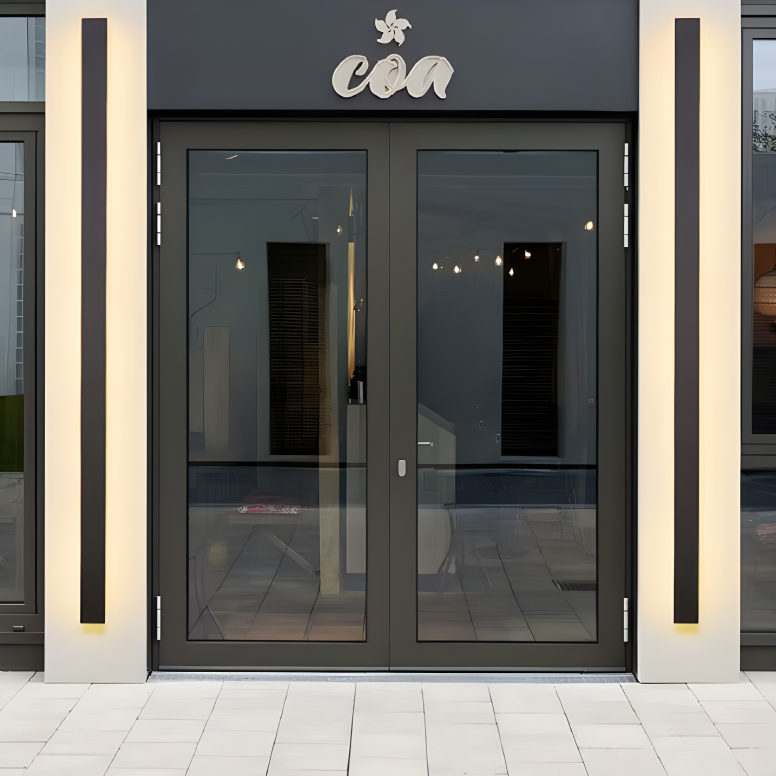 Modern glass doors with a brand logo above them on a building facade.
