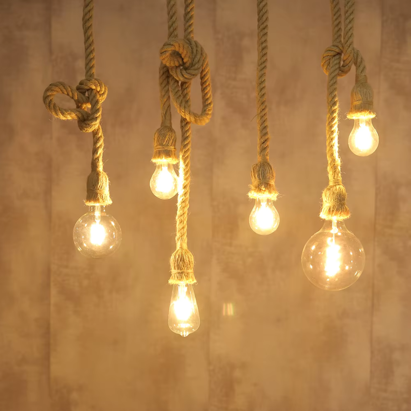 Vintage-style light bulbs hanging from knotted ropes against a textured wall.