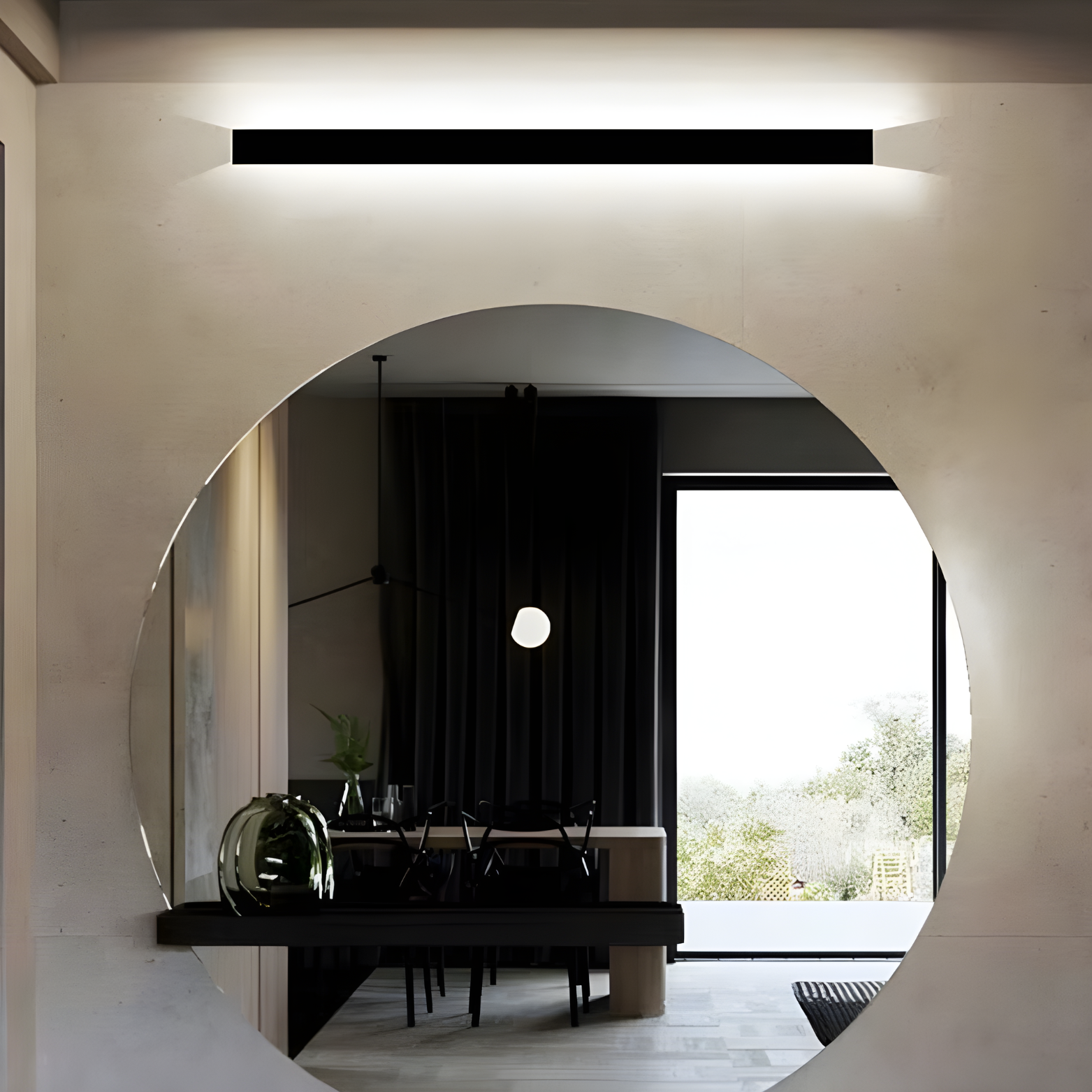 Modern interior with a round mirror reflecting a dining area.