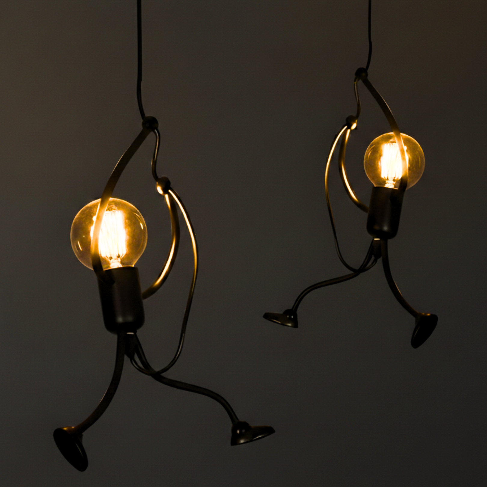 Two light bulb characters hanging against a dark background