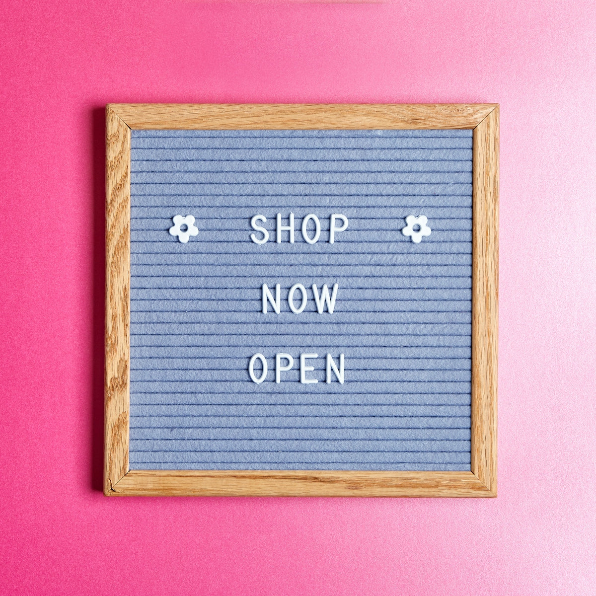 a sign that says shop now open on a pink wall