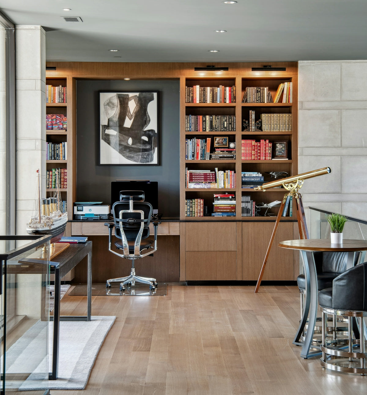 Modern home office with bookshelves and telescope.