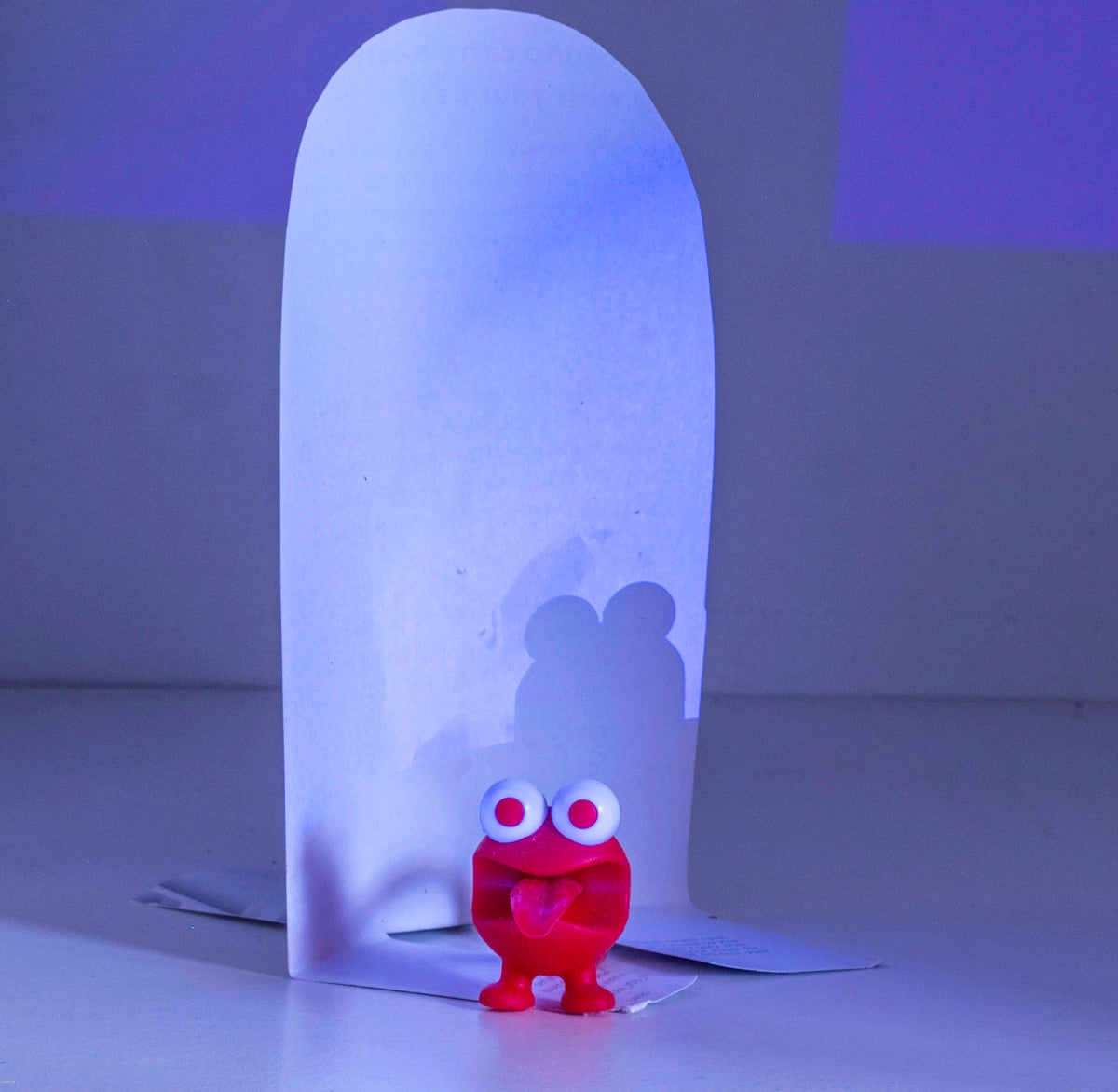A small red creature stands before a tall white structure.