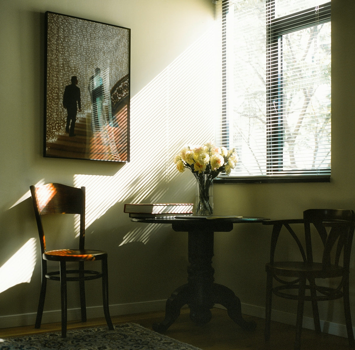Sunlight streams into a room with flowers and chairs.