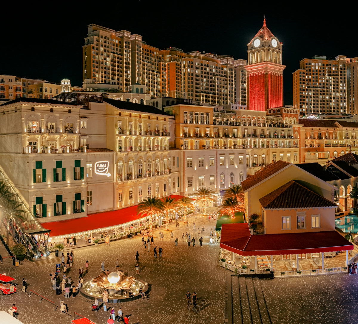 Busy european-style plaza at night with illuminated buildings.