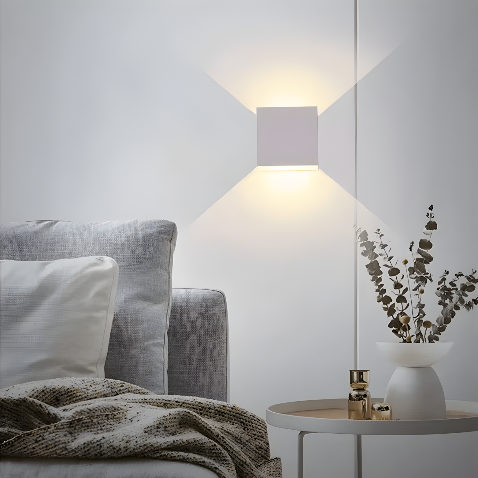 Modern living room with a gray sofa, white pillows, and a small table with decorative items.