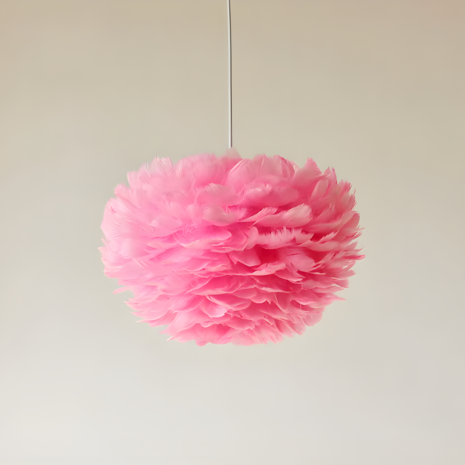 Pink tissue paper pom-pom hanging against a plain background