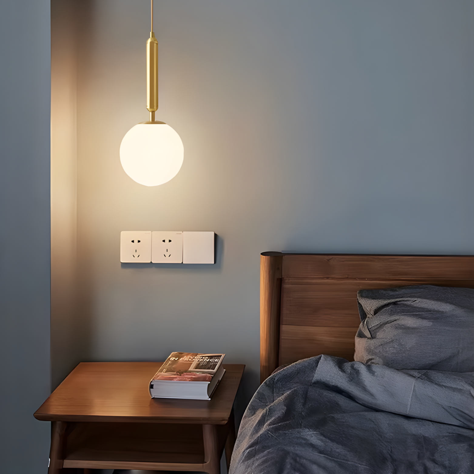 Bedroom with wooden nightstand, book, and hanging light fixture.