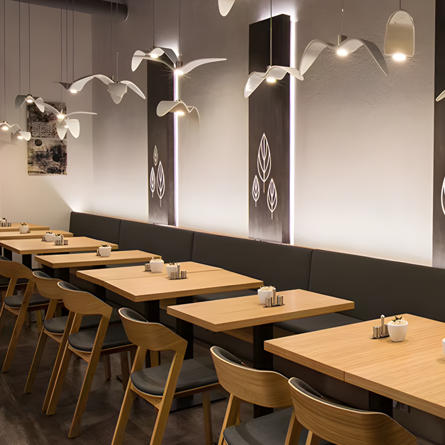 Modern restaurant interior with wooden tables and chairs, decorative wall lights, and black walls.