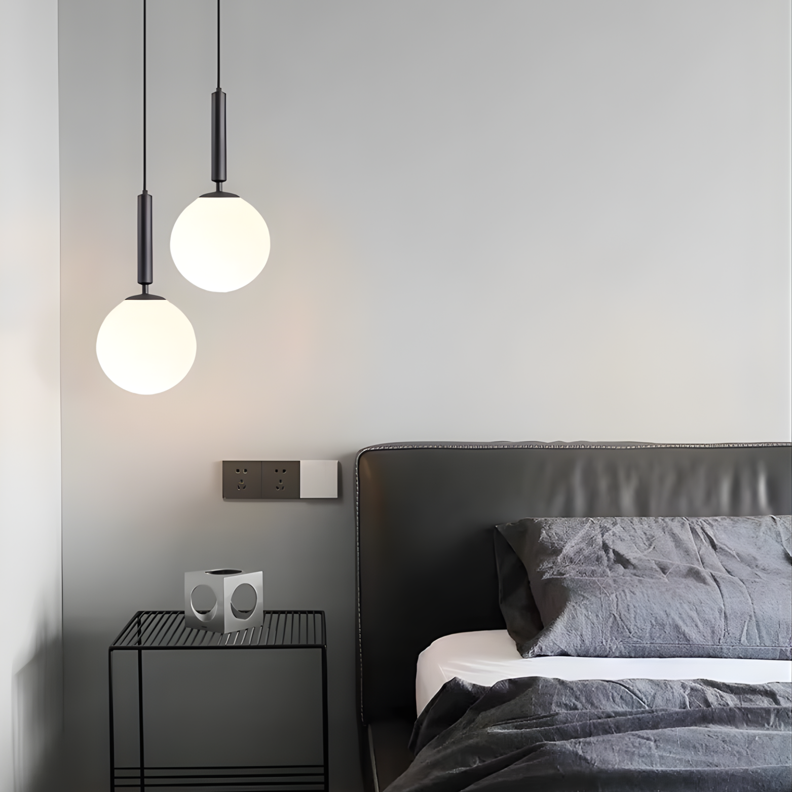 Modern bedroom with pendant lights, nightstand, and bed.