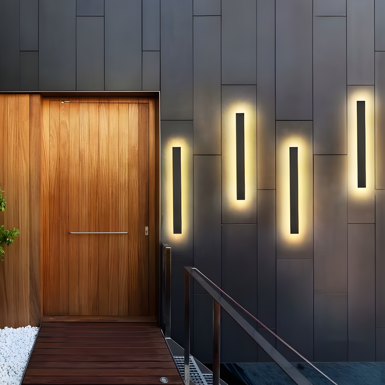 Modern entrance with wooden door and illuminated wall lights on a dark tiled wall.