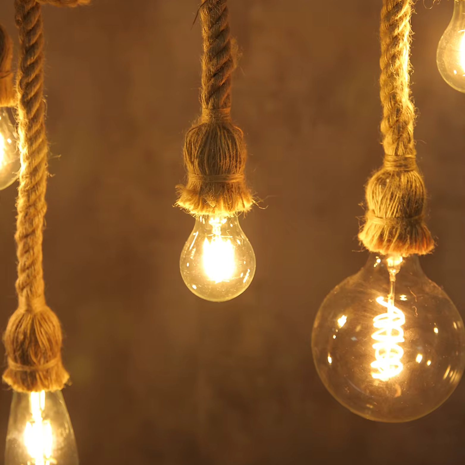Vintage light bulbs hanging by ropes with a warm glow on a dark background