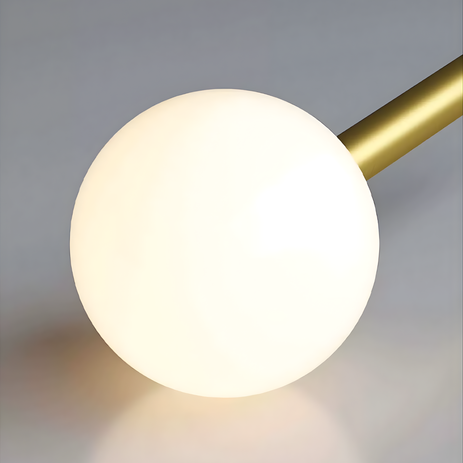 Modern wall lamp with a spherical white shade and gold arm on a gray background