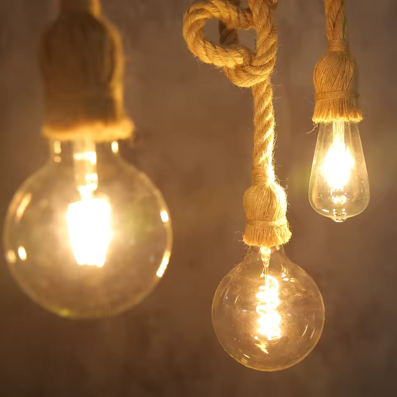 Three lit light bulbs hanging by ropes against a dark background