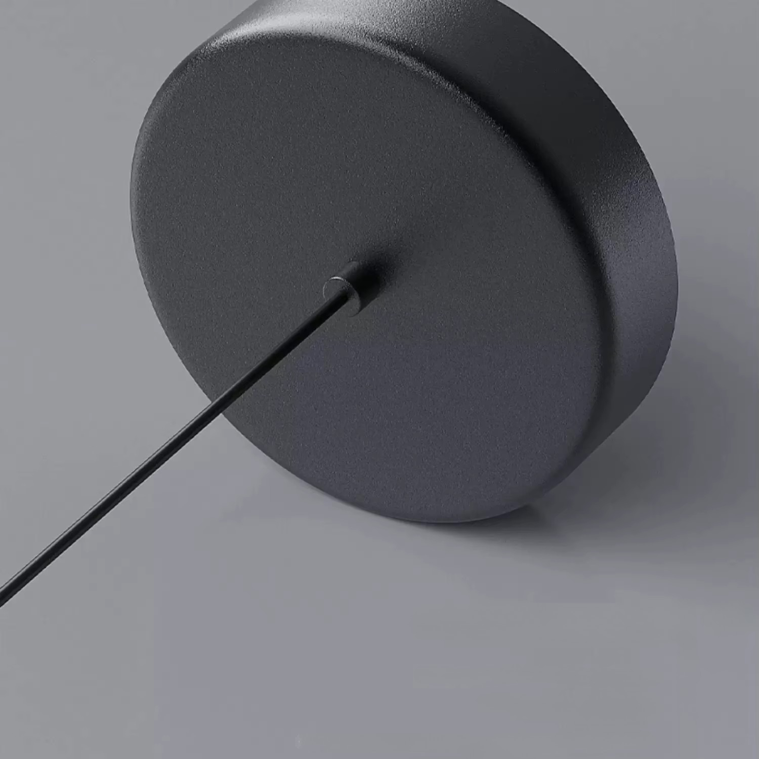 Black cylindrical object with a thin rod on a gray background