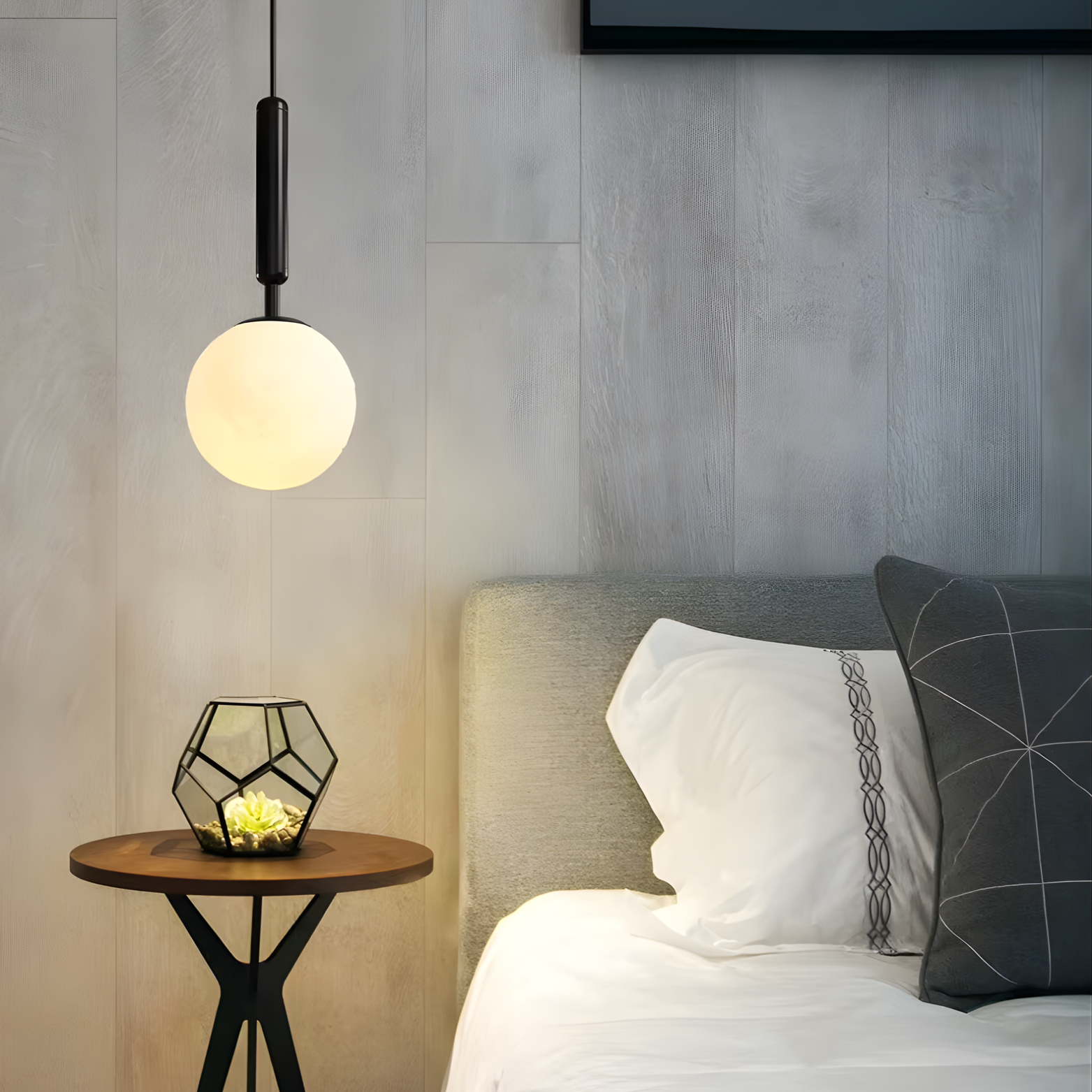 Modern bedroom with pendant light, side table, and bed with pillows.