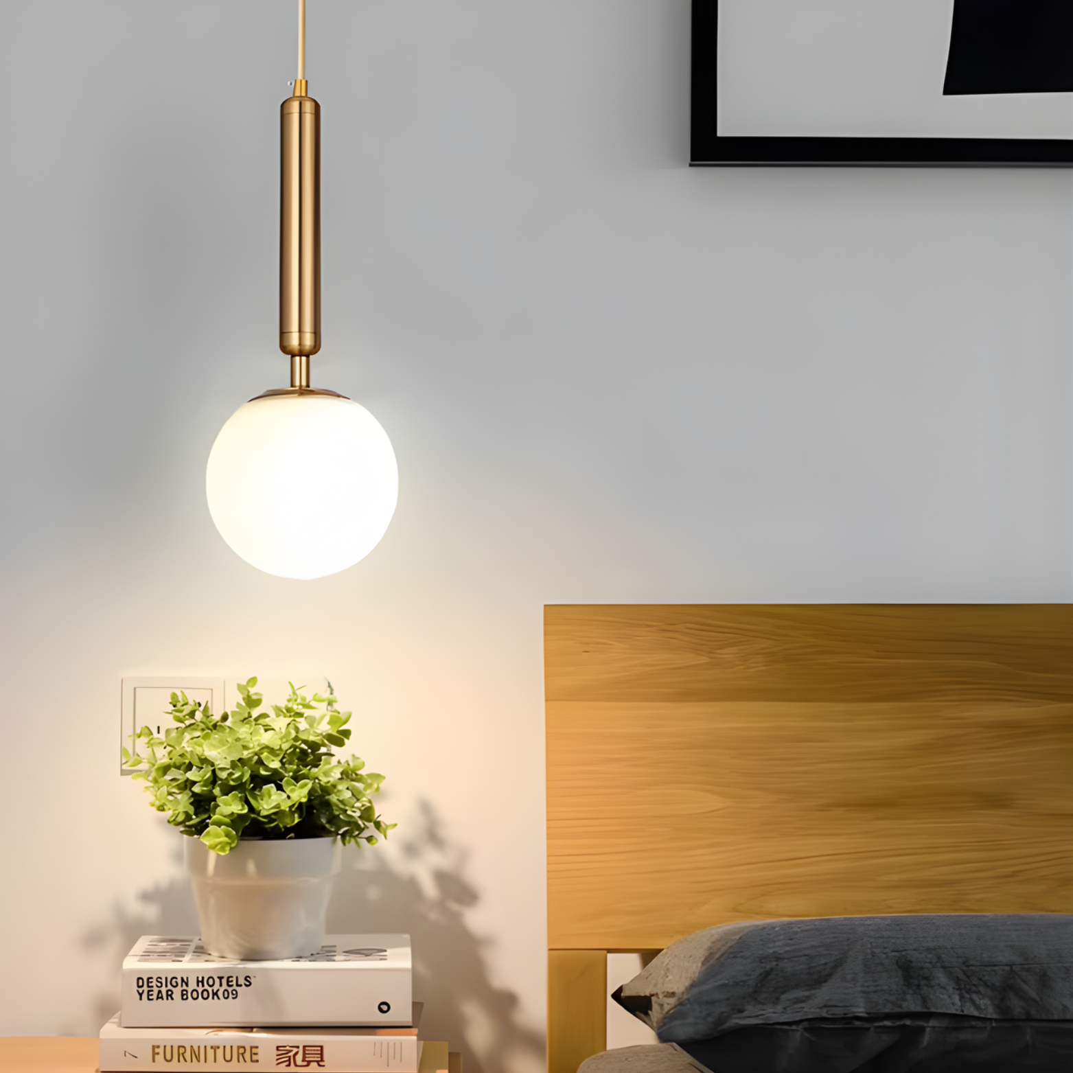 Pendant light fixture above a bed with a plant and books on a nightstand.