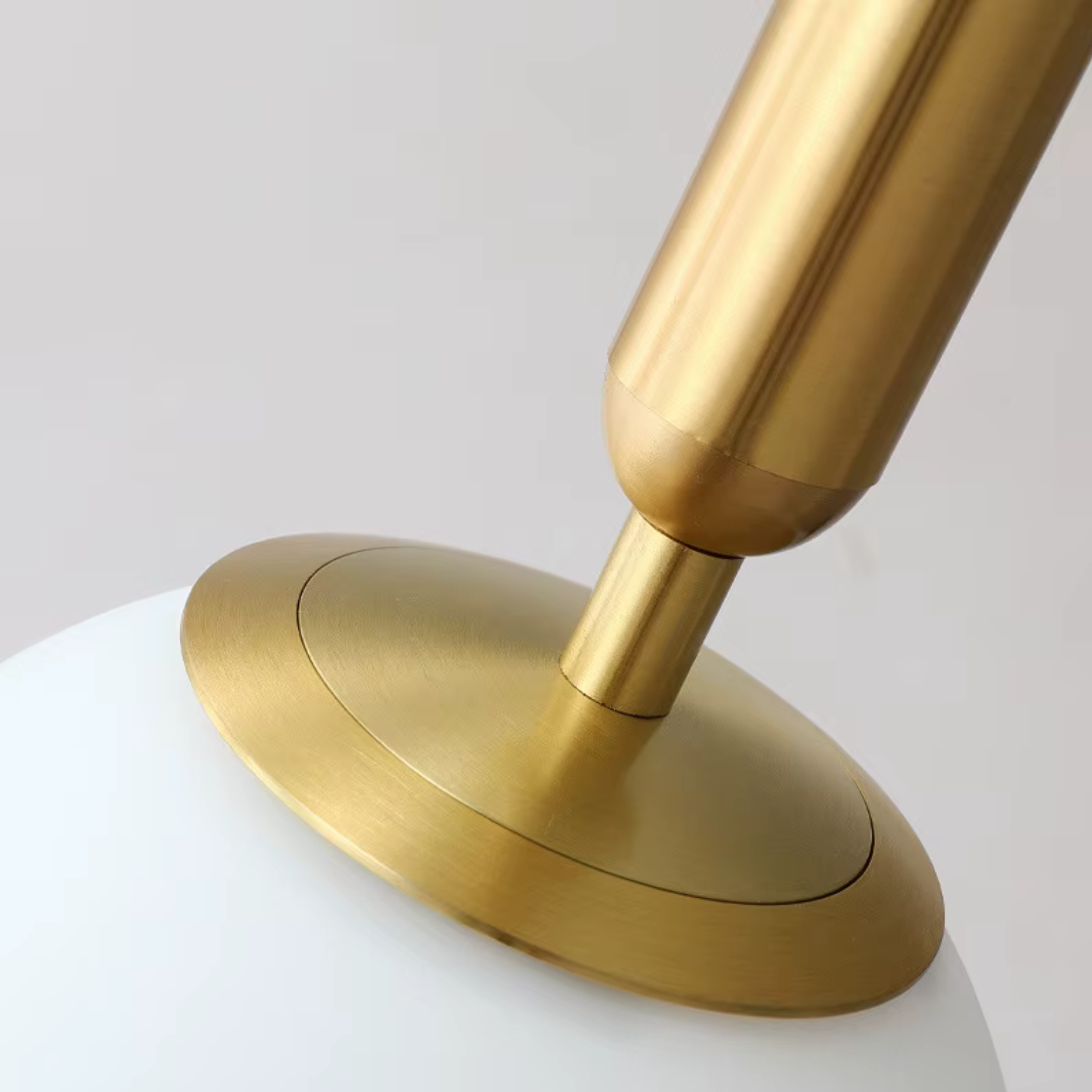 Close-up of a gold lamp with a white base on a light gray background