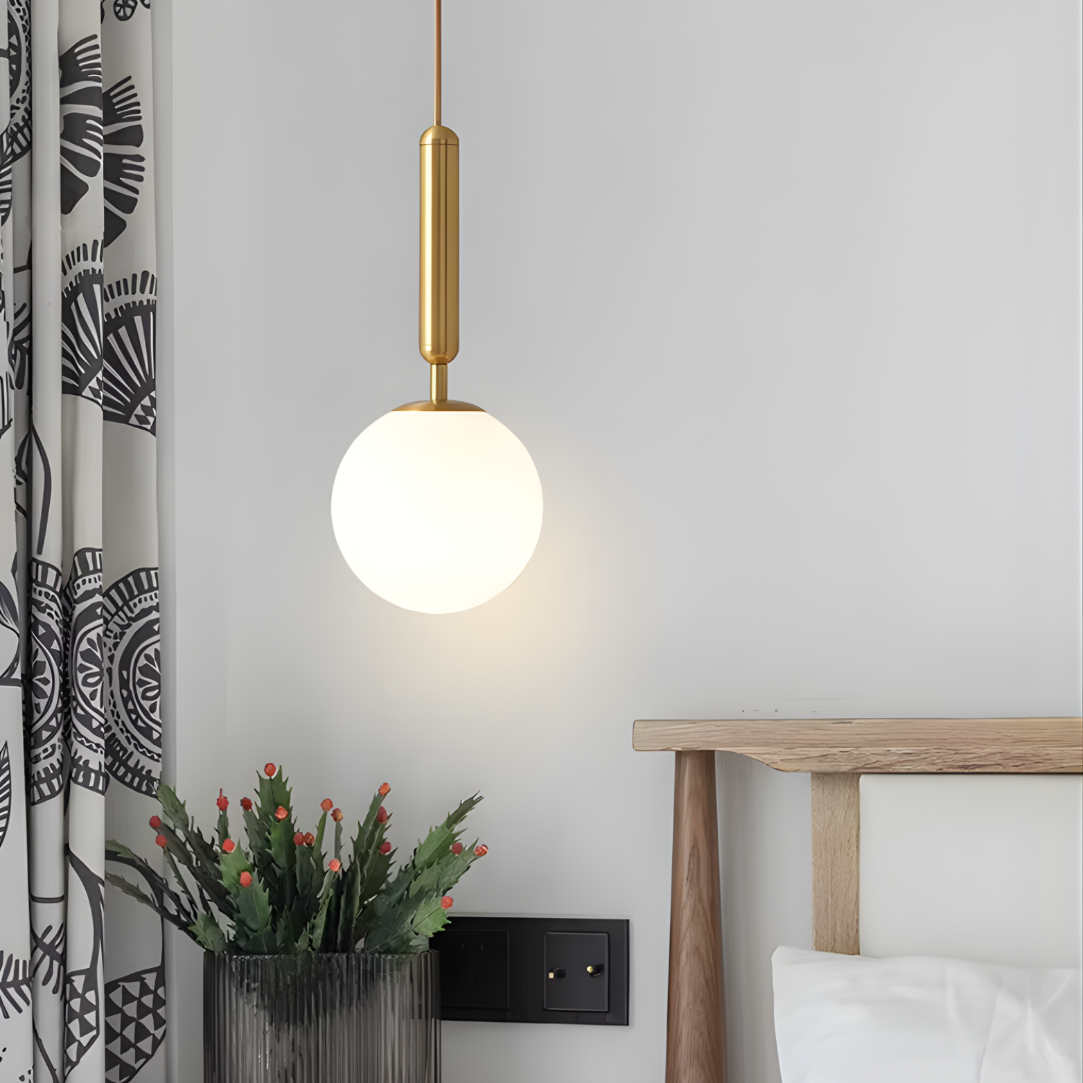 Modern pendant light fixture in a bedroom setting with a curtain and bed visible.
