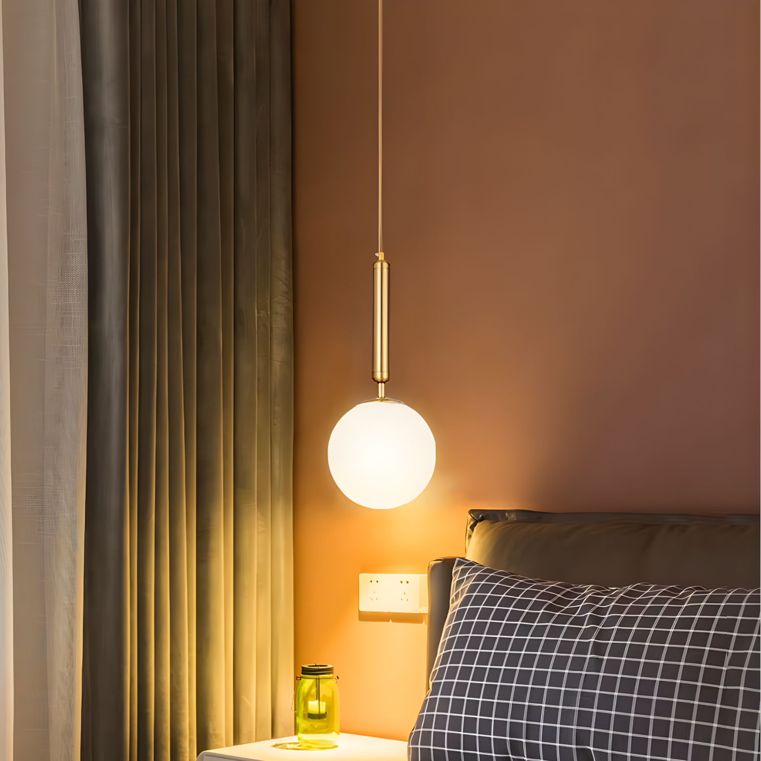 Pendant light hanging above a bed with a checkered pillow in a bedroom setting.