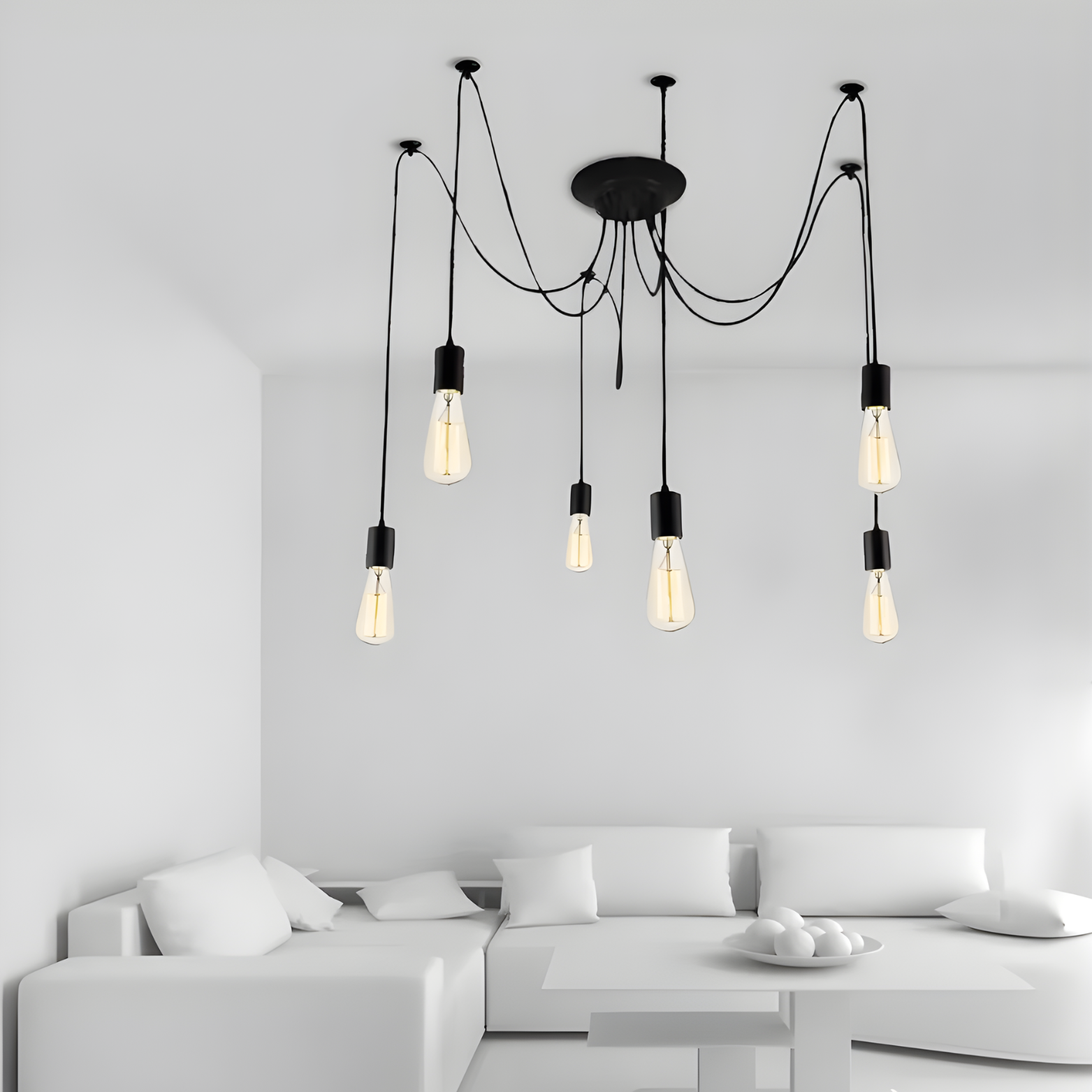 Modern chandelier with multiple light bulbs hanging above a white sofa in a minimalistic room.