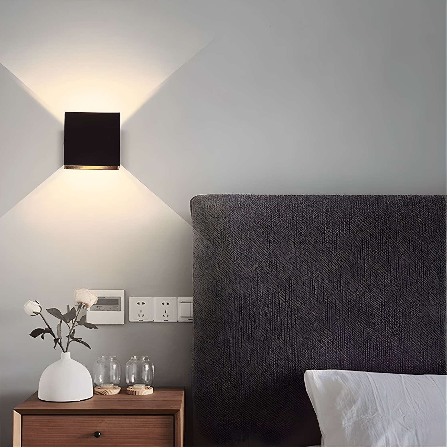 Modern bedroom with a dark headboard, wooden nightstand, and wall-mounted light fixture.