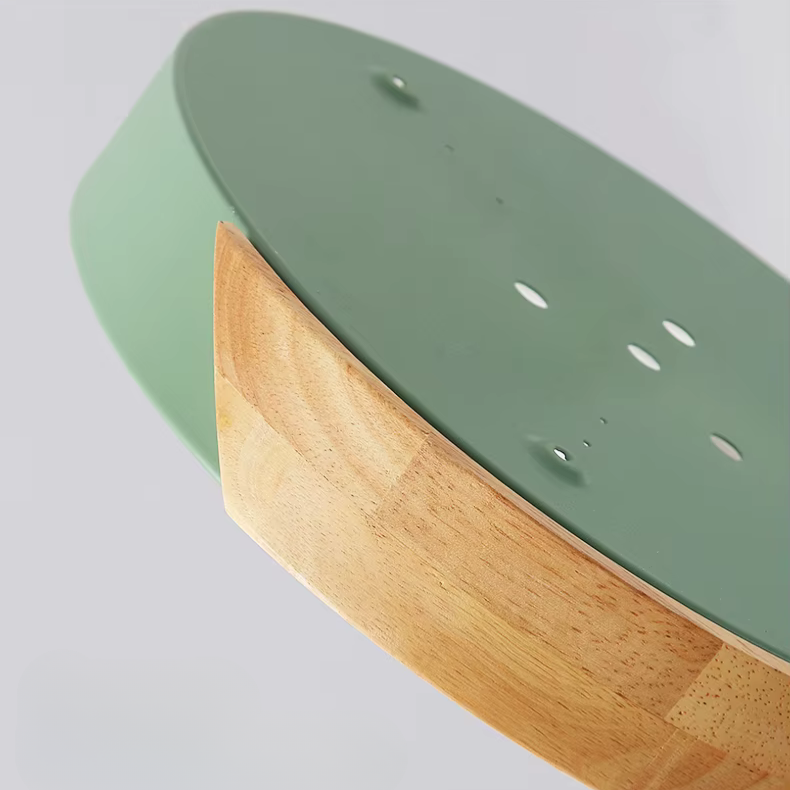 Close-up of a skateboard with green deck and wooden grip tape on a light gray background