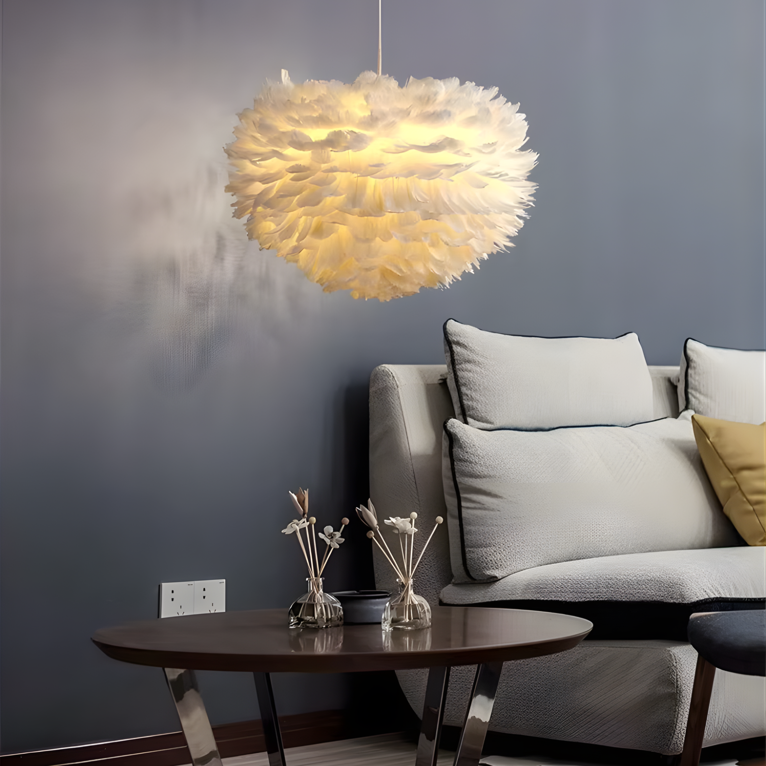 Modern living room with a feathered pendant light, gray sofa, and wooden table.