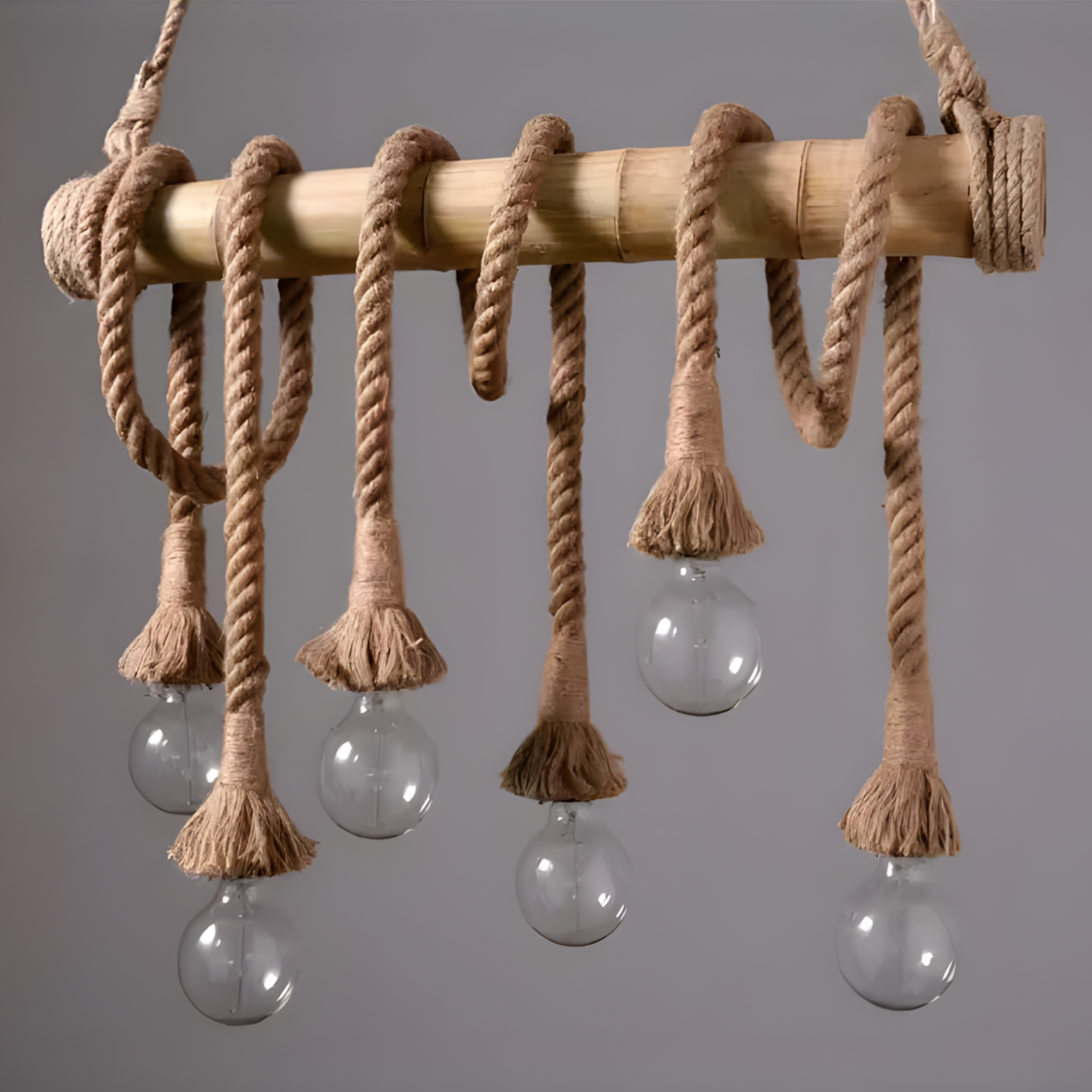 Chandelier with wooden rod and ropes hanging from it against a gray background