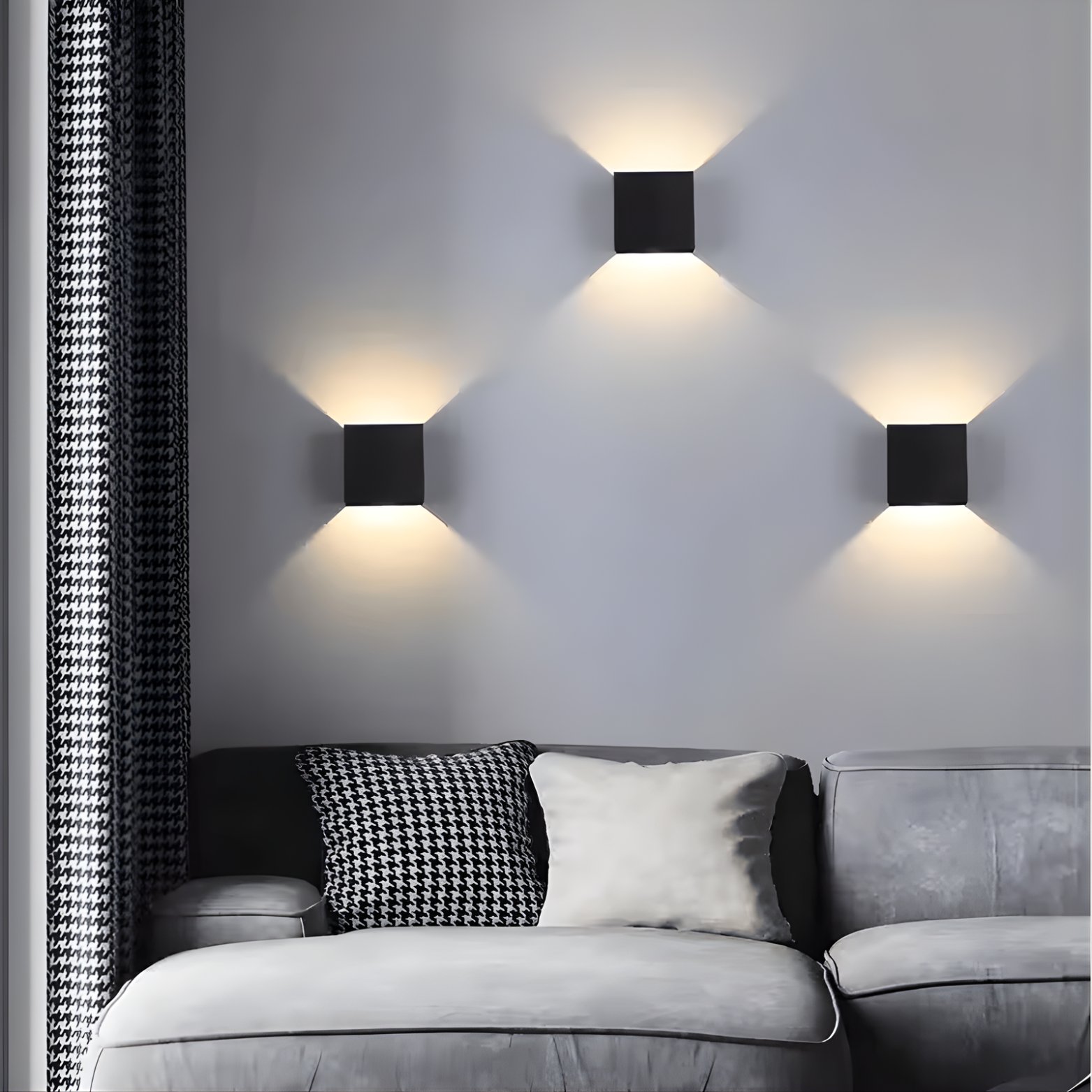 Modern wall lights on a gray wall above a gray sofa with decorative pillows.
