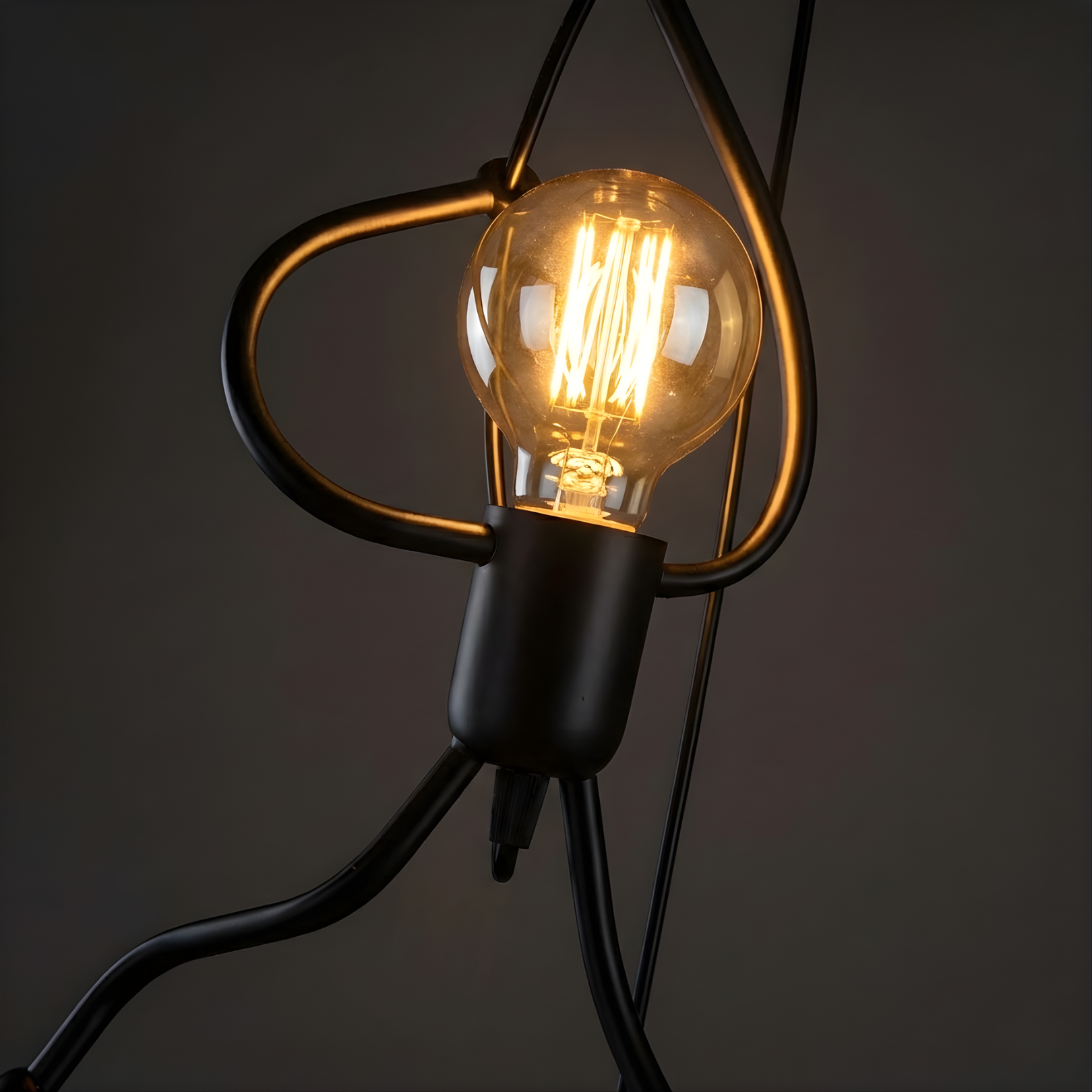 Vintage-style light bulb with coiled black wires on a dark background